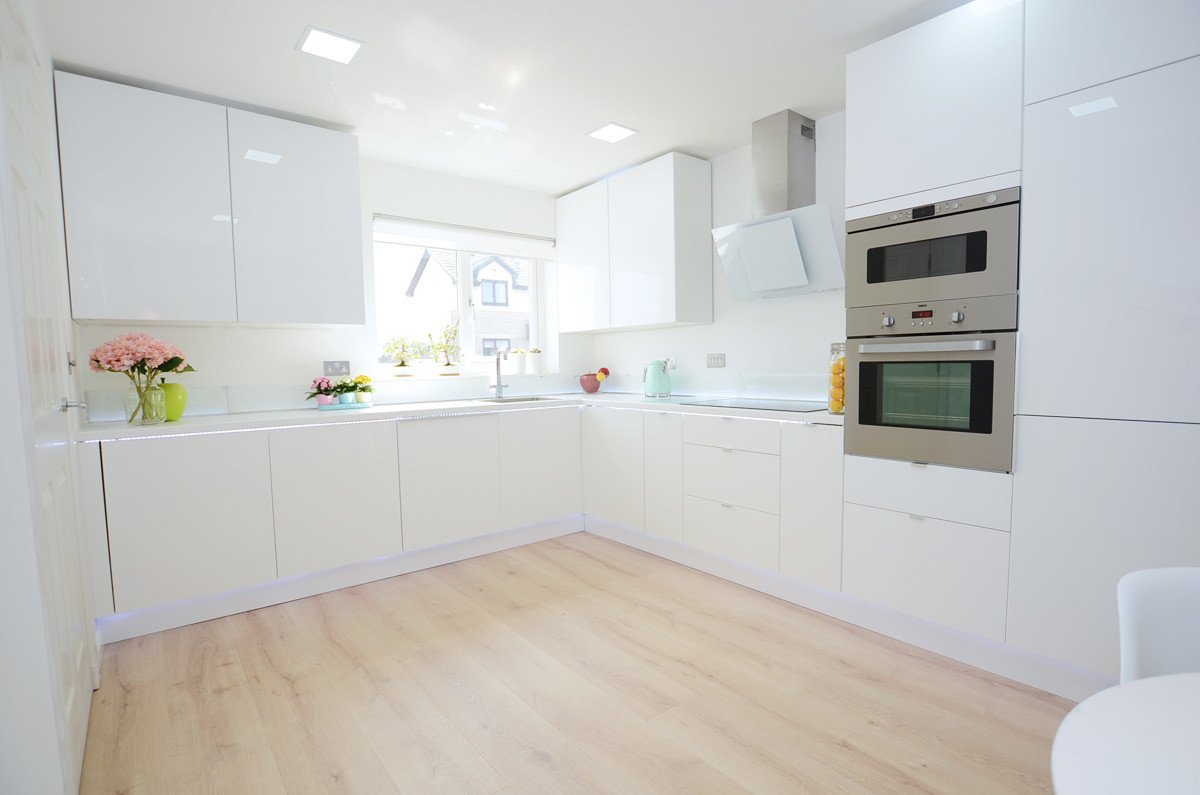 White kitchen with pale wood floors and silver appliances