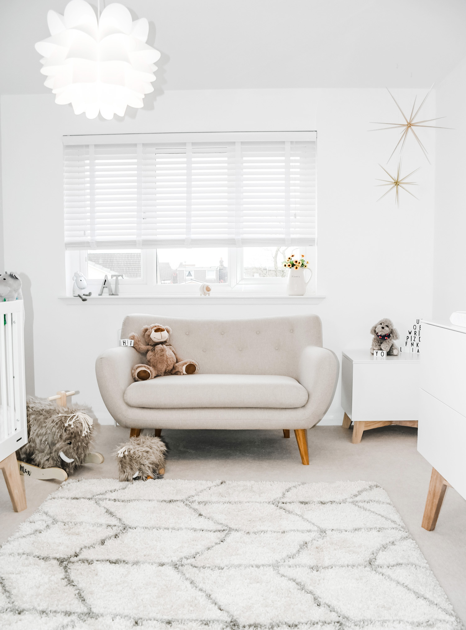 Neutral nursery with beige retro sofa and chevron rug