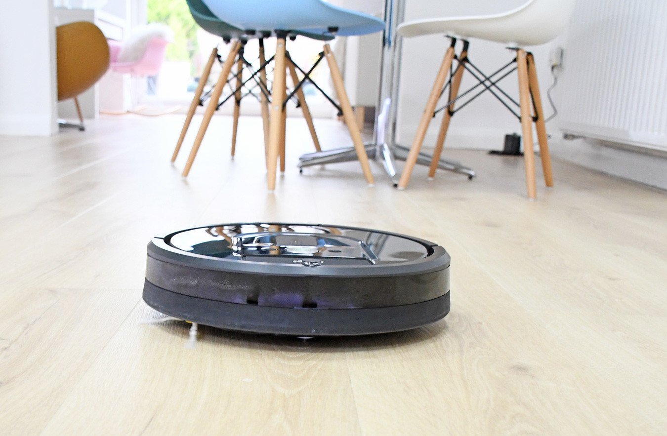 Roomba Robot Vacuum Cleaner in action cleaning pale wood kitchen floor