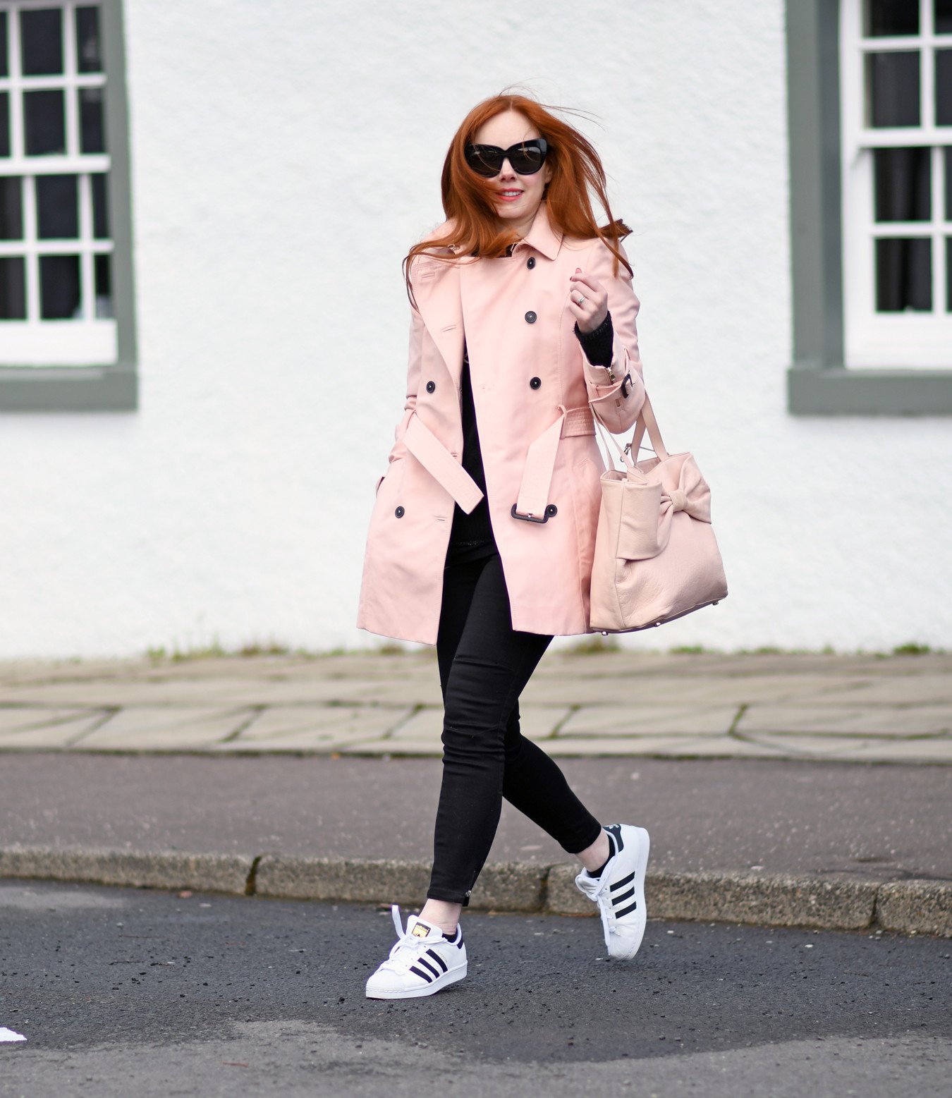 casual spring outfit: pink trenchcoat with black jeans and Adidas Superstar sneakera