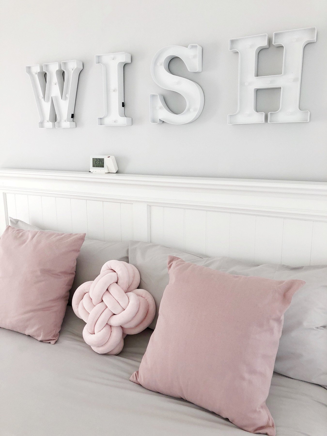 pink and grey bedroom with kotted cushion and LED marquee lights