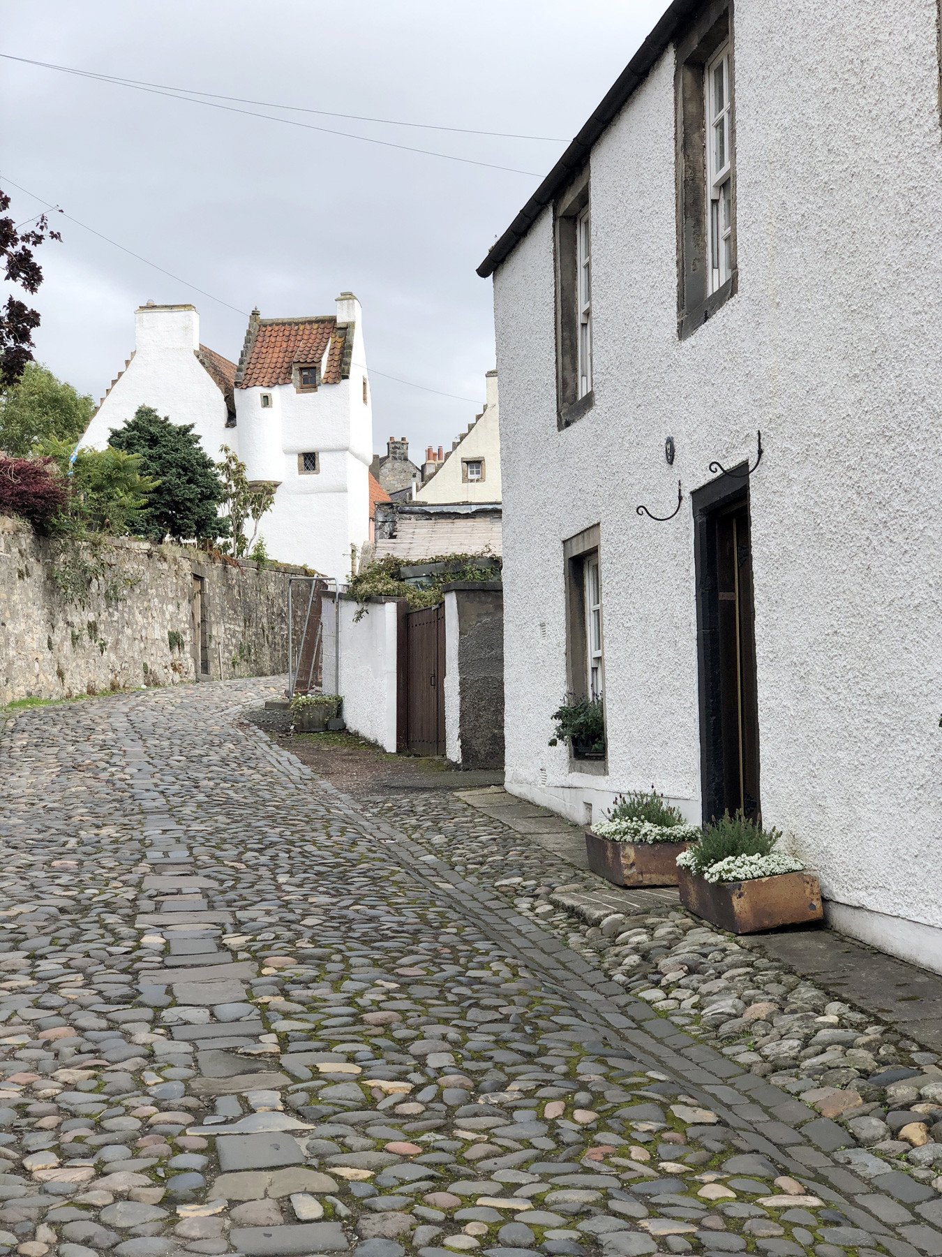 winding, cobbled street with old white houses in Culross, Scotland
