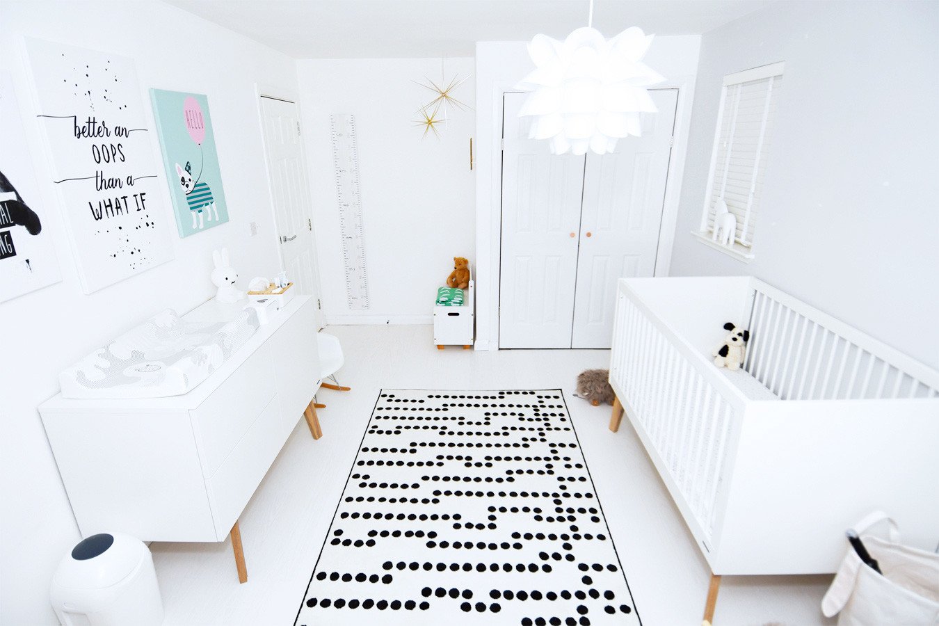 all-white nursery with black and white rug and white wooden floor