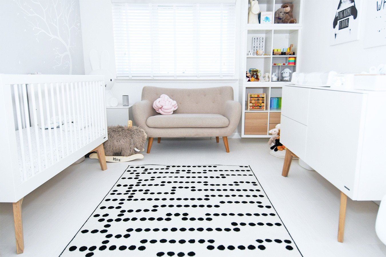 neutral nursery with black and white rug and white furniture