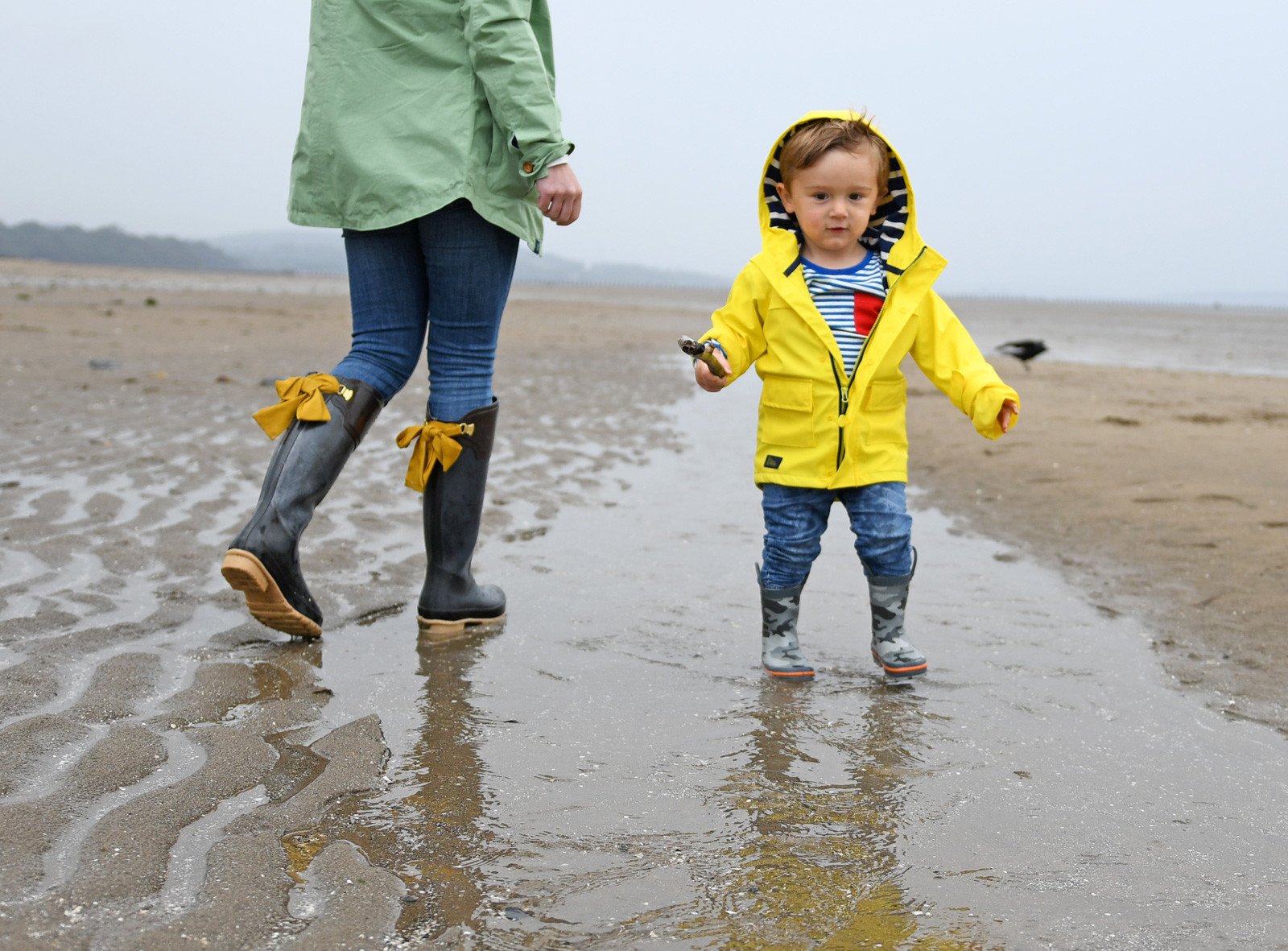 toddler on the beach in a bright yellow raincoat