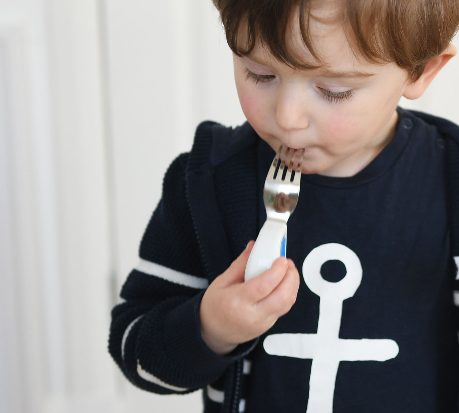 toddler using fork to eat fruit