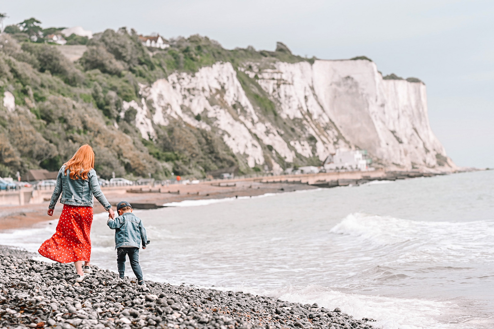 Amber and Max walking along a pebble beach at the white cliffs of Dover