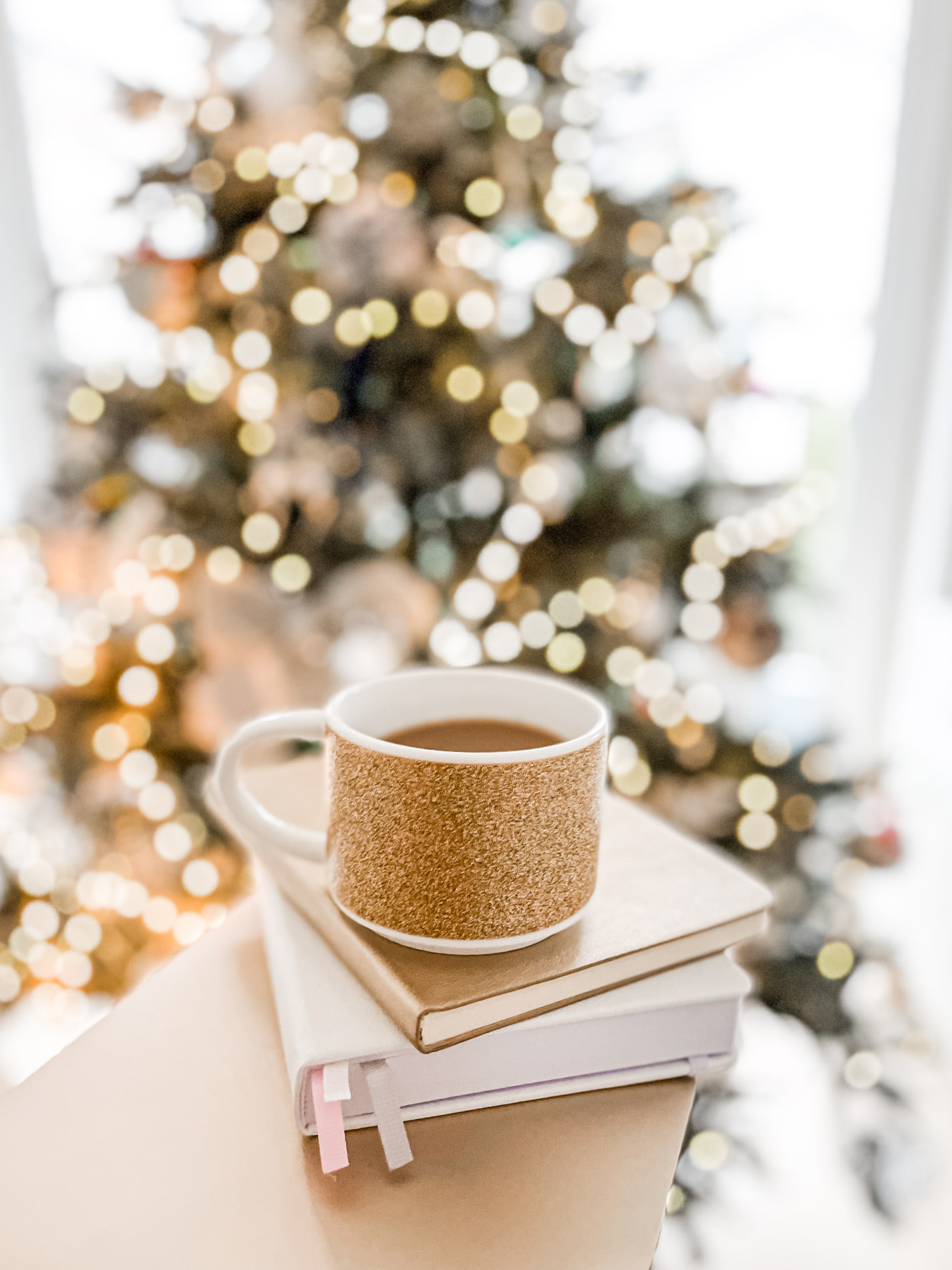 coffee cup and books in front of a Christmas tree