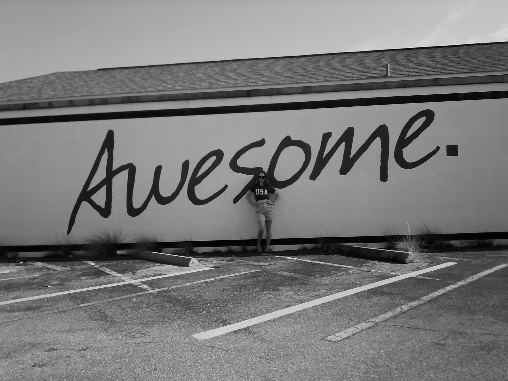 Amber stands against a wall which has the word 'Awesome" written on it