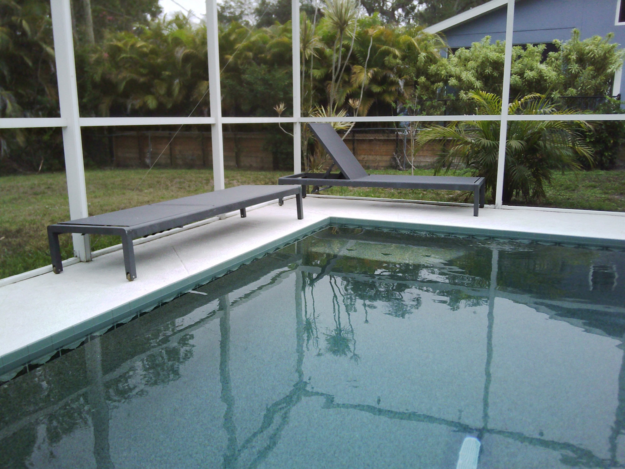 An empty swimming pool in Florida. A sunlounger is reflected in the water