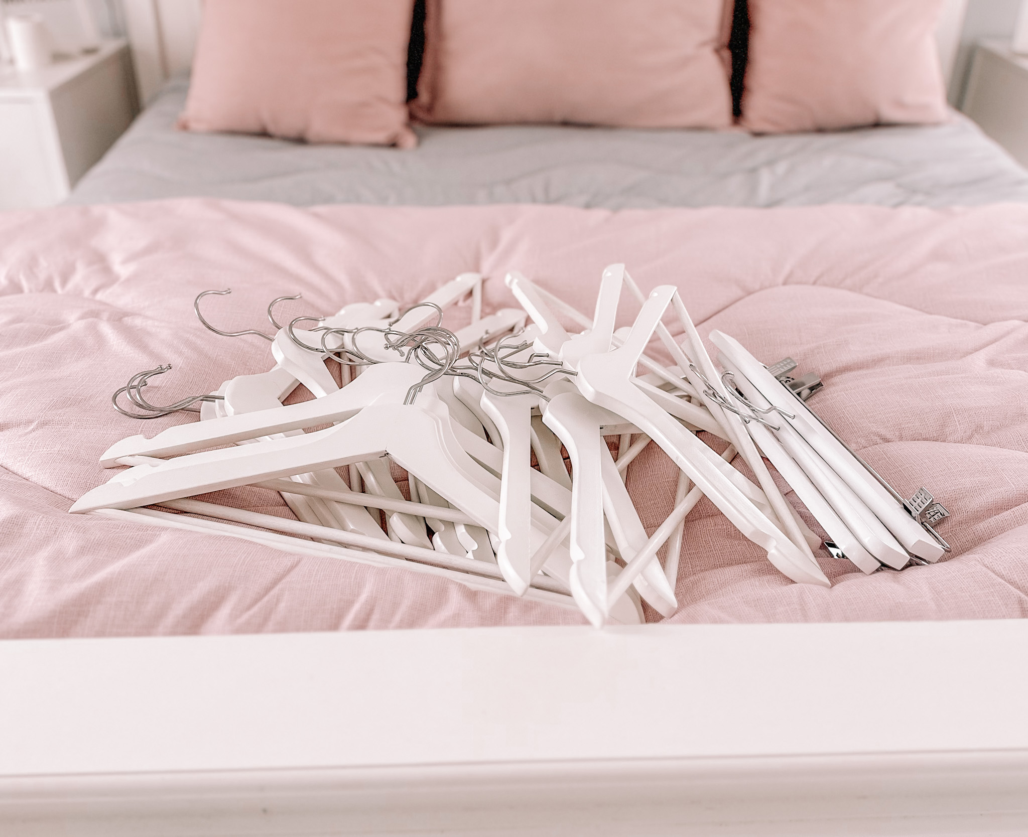 white coathangers on pink bed